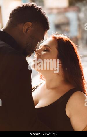 Ritratto di felice coppia interracial che posa sullo sfondo della città, felici amanti etnici misti sorridenti e guardandosi l'un l'altro, giovane afroamericano Foto Stock