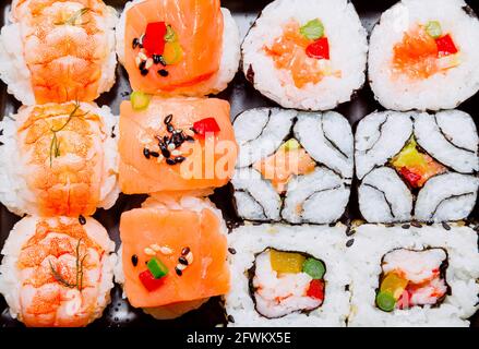 Diverse varietà di sushi pronti da mangiare a base di riso, pesce, alghe nori, crostacei, verdure e verdure. Piatto tipico di cucina Giapponese. Foto Stock