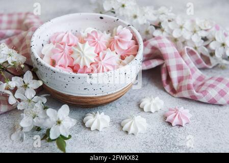 Piccole meringhe bianche e rosa nel recipiente in ceramica sfondo concreto Foto Stock