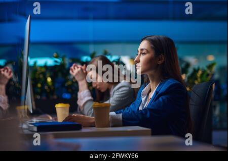 Donne stanche seduti al tavolo in ufficio notturno Foto Stock