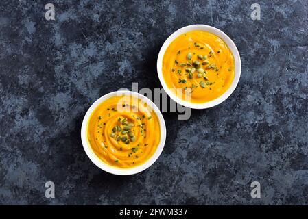 Purea di zucca in ciotola su sfondo di pietra blu con spazio libero per il testo. Concetto di alimentazione sana. Vista dall'alto, disposizione piatta Foto Stock