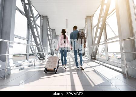 Viaggio di vacanza. Vista posteriore della coppia Nera Passeggiate con bagagli in aeroporto Foto Stock
