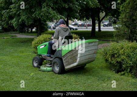 Lavori estivi nel parco. Il giardiniere taglia l'erba su una macchina speciale. Foto Stock