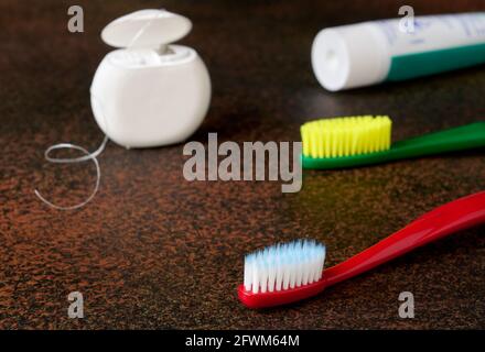 Articoli per l'igiene orale con fondo scuro in primo piano, spazzolini da denti, filo interdentale Foto Stock