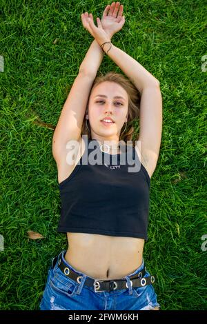Giovane donna che posa sull'erba nel campus universitario Foto Stock
