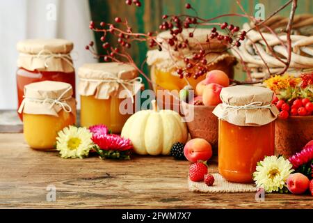 Marmellate in vasi di vetro tra frutta e verdura. Cibo sano Foto Stock