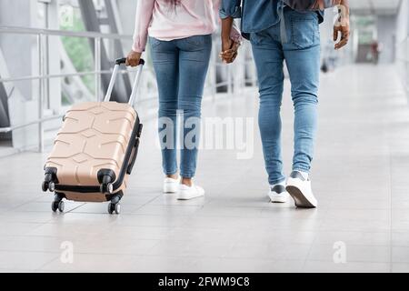 Trasporto aereo. Immagine ritagliata della coppia nera camminando con i bagagli in aeroporto Foto Stock