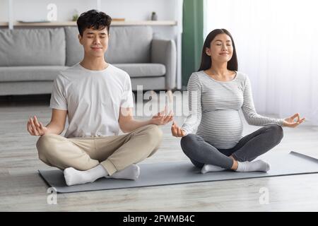Rilassato aspettandosi una coppia asiatica che pratica yoga insieme Foto Stock