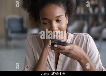 Giovane donna africana che dettava messaggio audio sul cellulare. Foto Stock