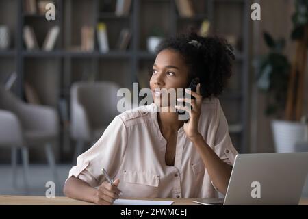 Sognante giovane donna afroamericana che tiene la telefonata. Foto Stock