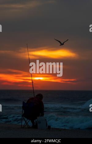 Un uomo pesca nel surf all'alba sull'isola di Assateague National Seashore. Foto Stock