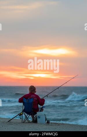 Un uomo pesca nel surf all'alba sull'isola di Assateague National Seashore. Foto Stock