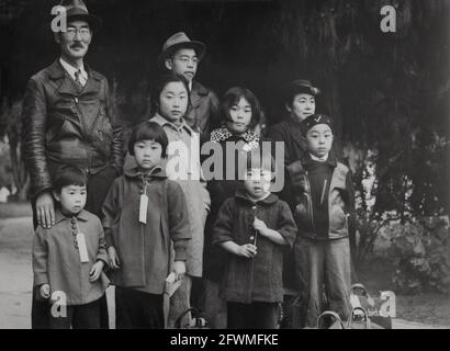 Seconda guerra mondiale i membri della famiglia Mochida in attesa di un autobus di evacuazione, indossando etichette di identificazione per aiutare a mantenere intatta l'unità di famiglia durante tutte le fasi di evacuazione, durante la seconda guerra mondiale. Foto di Dorothea Lange Hayward, CA, 8 maggio 1942 Foto Stock