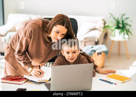 Mamma e figlio fanno i compiti a scuola su un computer portatile Foto Stock