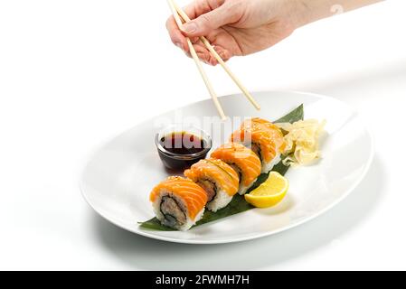 Sushi e salsa di soia in una ciotola bianca e tavolo bianco con chopsticks di legno. Cibo giapponese. Set di sushi di pesce giapponese. Menu sushi bar. Foto Stock