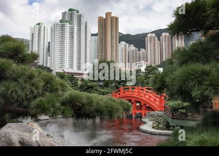 Ponte rosso nel giardino di Nan Lian con edifici ad appartamenti densamente impaccati sullo sfondo, Hong Kong, RPC Foto Stock