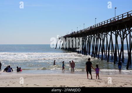 Gli amanti della spiaggia si rinfrescano nell'oceano vicino al molo di Kure Beach, North Carolina. Foto Stock