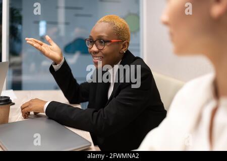 Donna d'affari nera che parla con i colleghi durante la riunione Foto Stock