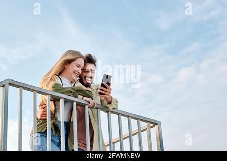 Giovane coppia multirazziale sorride mentre stanno guardando un telefono Foto Stock