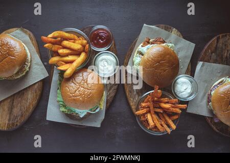 Vista ad alto angolo di vari hamburger con patatine fritte servite su tavole di legno Foto Stock