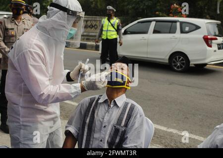 Madiun, Indonesia. 23 maggio 2021. Le persone, sia in città che al di fuori della regione, se non indossano una maschera e non mostrano un certificato gratuito Covid-19, devono essere sottoposte a un tampone antigenico mobile fornito dagli agenti di polizia del Madiun Resort. Il personale congiunto ha attività nel contesto di una campagna per prevenire il virus della corona o la covid-19 socializzando il protocollo sanitario 5M, vale a dire lavarsi le mani con sapone con acqua corrente, indossare maschere, mantenere la distanza, limitare la mobilità e stare lontano dalla folla. (Foto di Ajun Ally/Pacific Press/Sipa USA) Credit: Sipa USA/Alamy Live News Foto Stock