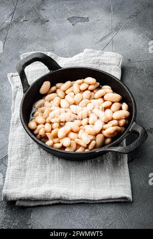 Set di fagioli bianchi in scatola, in padella di ghisa, su fondo di pietra grigia Foto Stock