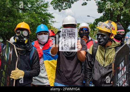 I dimostranti che fanno parte della linea anteriore indossano maschere a gas e proteggono dai proyectile con un sospiro che recita: "Il più proiettile che hai sparato a noi tornerà da te" mentre scontri e rivolte si evolvono a Medellin, Colombia dopo dimostranti e polizia antisommossa (ESMAD) durante una dimostrazione che si è intensificata a scontri dopo le telecamere di sicurezza e il commercio sono stati colpiti dalla protesta. A Medellin, Antioquia, Colombia il 22, 2021. Foto Stock