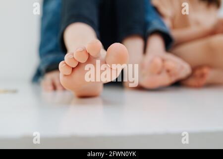 Piede del bambino vicino. Con unghie leggermente sopravcrescita ma pulite. Resto è sfocato Foto Stock