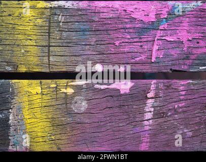 Tavole di legno testurizzate con strisce astratte di vernice spray gialla, rosa e blu. Foto Stock