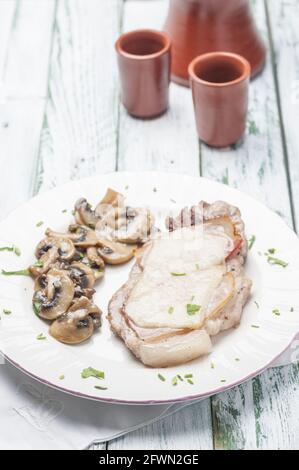Piatto di orche costolette con pancetta e formaggio accompagnati da funghi all'aglio Foto Stock