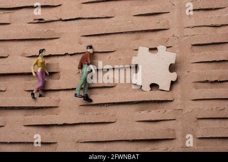 pezzo di puzzle e minuscola figurina di uomo e donna miniatura modello in vista Foto Stock