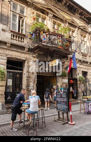 Persone non identificate si appendono all'ingresso del Giardino di Szimpla Ruin club a Budapest Foto Stock