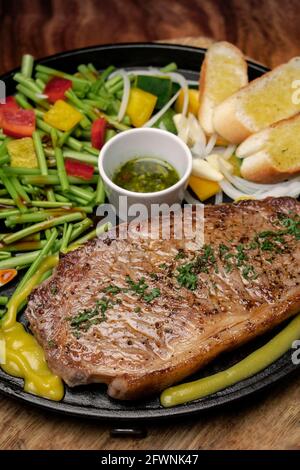 bistecca di manzo al filetto biologico sizzler su piatto piatto caldo con verdure miste e salsa chimichurri Foto Stock