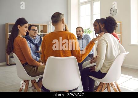 Primo piano della vista posteriore del gruppo di persone seduto in cerchio discussione in un ufficio moderno Foto Stock