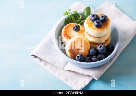 Frittelle di formaggio cottage. Cheesecakes dal formaggio di cottage, deliziosa colazione, tradizionali frittelle dolci russe. Con mirtillo, menta e miele. Foto Stock