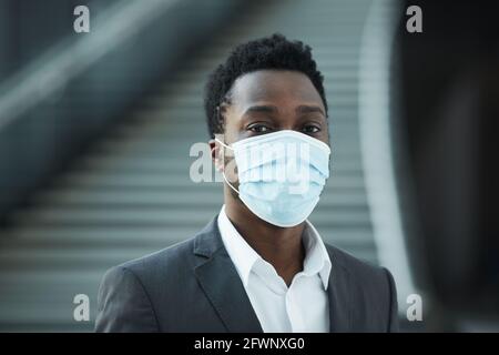 Ritratto di successo afro-americano uomo d'affari indossare maschera mentre si guarda la fotocamera in ufficio edificio, copia spazio Foto Stock