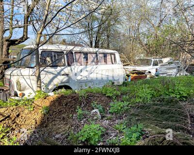 Un vecchio autobus rotto in un'automobile discarica tra i rifiuti. Foto Stock