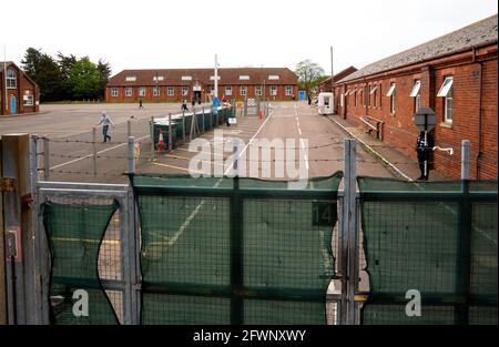 Dal settembre 2020, le ex caserme MOD Napier, Folkestone, sono state utilizzate dall'ufficio di casa per fornire alloggi temporanei per i rifugiati maschi adulti che cercano asilo nel Regno Unito. Il campo è gestito da Clearspring Ready Homes. In precedenza, circa il 25% dei rifugiati nei campi ha dato risultati positivi per Covid-19, a causa di una grave mancanza di agevolazioni per le distanze sociali. Le caserme sono state dichiarate inadatte all'alloggio umano anche da ispettori indipendenti. L'alta recinzione intorno alle baracche di Napier è sormontata da filo spinato. Nella foto, vista sul cancello delle baracche di Napier. Foto Stock