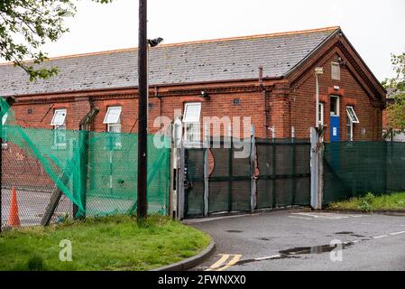 Dal settembre 2020, ex MOD Napier Barracks, Folkestone, sono state utilizzate dall'ufficio di casa per fornire alloggio temporaneo per i rifugiati maschi adulti che cercano asilo nel Regno Unito. Il campo è gestito da Clearspring Ready Homes. In precedenza, circa il 25% dei rifugiati nei campi ha dato risultati positivi per Covid-19, a causa di una grave mancanza di agevolazioni per le distanze sociali. Le caserme sono state dichiarate inadatte all'alloggio umano anche da ispettori indipendenti. L'alta recinzione intorno alle baracche di Napier è sormontata da filo spinato. Nella foto, ingresso alla caserma di Napier. Foto Stock