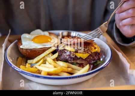 Primo piano di un hamburger di due metà in un piatto con patatine fritte. Foto Stock