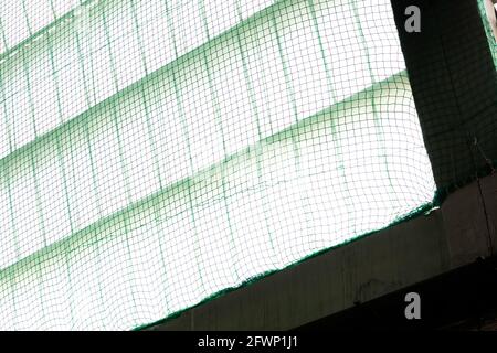 una rete di sicurezza di colore verde, posta sotto le finestre verticali per evitare il rischio di cadute durante i lavori Foto Stock