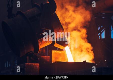 Colata di metallo fuso in ferro liquido dal contenitore della siviera allo stampo, alla fabbrica metallurgica industriale, alla fusione di fonderia, alla base dell'industria pesante. Foto Stock