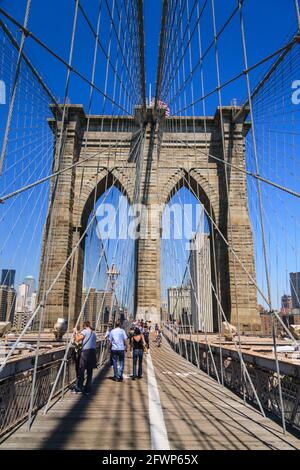 La gente cammina sul ponte di Brooklyn in una giornata soleggiata con cielo blu, New York City, New York, Stati Uniti Foto Stock