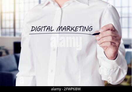 La mano dell'uomo d'affari tiene una penna e sottolinea le parole marketing digitale su uno schermo virtuale. Concetto di marketing aziendale. Foto Stock