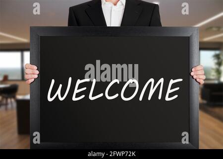 Uomo d'affari ha un grande cartello con il messaggio Benvenuto. Cartello di benvenuto. Foto Stock
