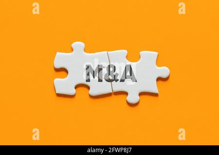 Pezzi di puzzle collegati con l'acronimo M&A. Fusione e acquisizione nel concetto di business. Foto Stock