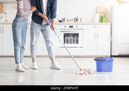 Irriconoscibile uomo e donna pulizia cucina, pavimento di pulizia Foto Stock