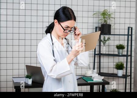 Ritratto di medico donna usando la sua tavoletta digitale in ufficio Foto Stock