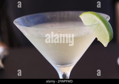 sponda di vetro smerigliato con bevanda da cocktail pallido e spicchio di lime come guarnizione sul bicchiere Foto Stock