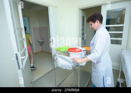 In una hall di un ospedale. Infermiere in camici da laboratorio tirando un trolley con cibo in pentole per i pazienti. 4 giugno 2019. Kiev Centro cittadino di neurochirurgia. K Foto Stock